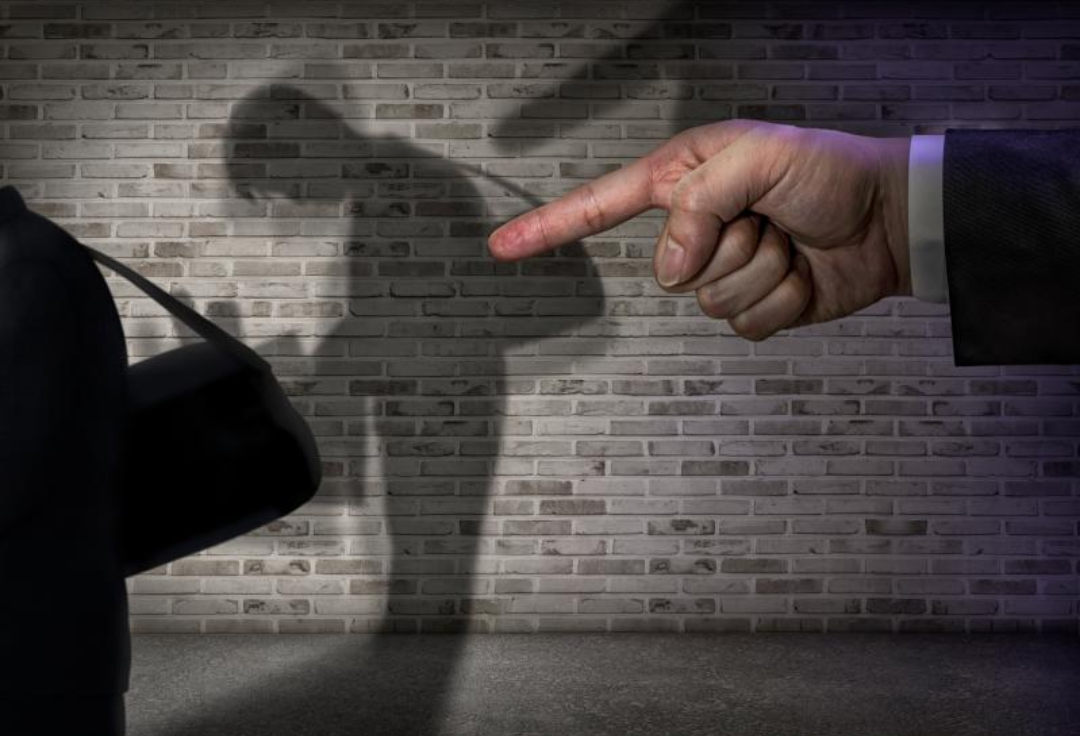 커다란 손가락이 풀이 죽어있는 남자에게 삿대질을 하고 있다.