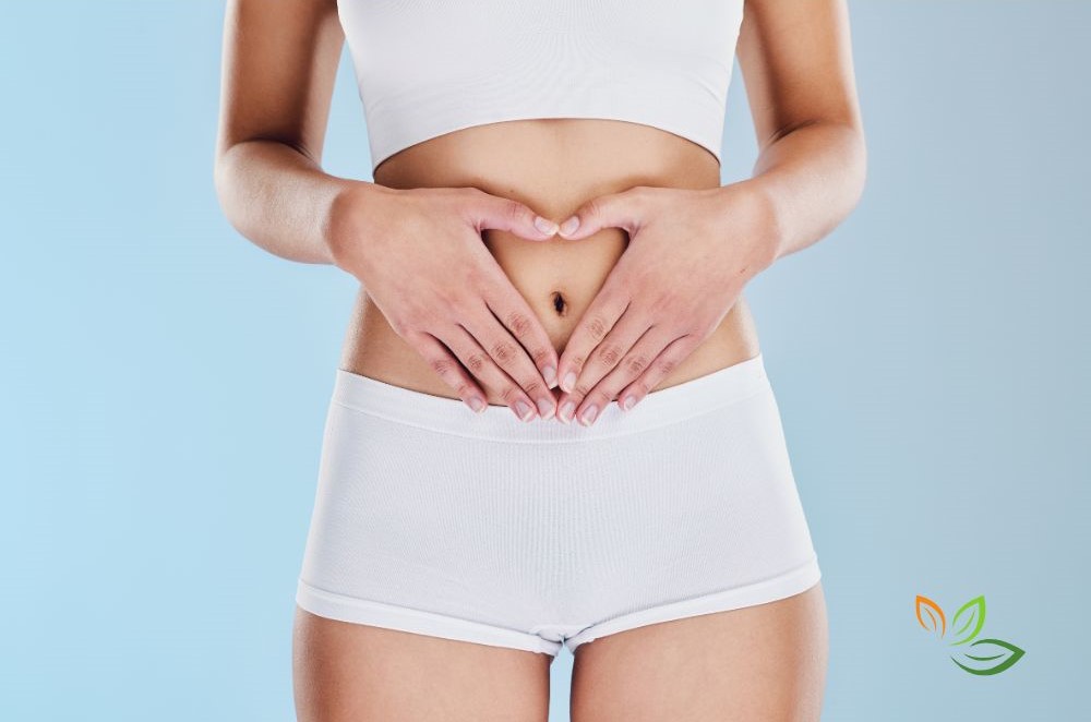 장 건강 관리를 나타내는 이미지 - 흰색 운동복을 입은 여성이 복부에 하트 모양으로 손을 올린 모습 via canva