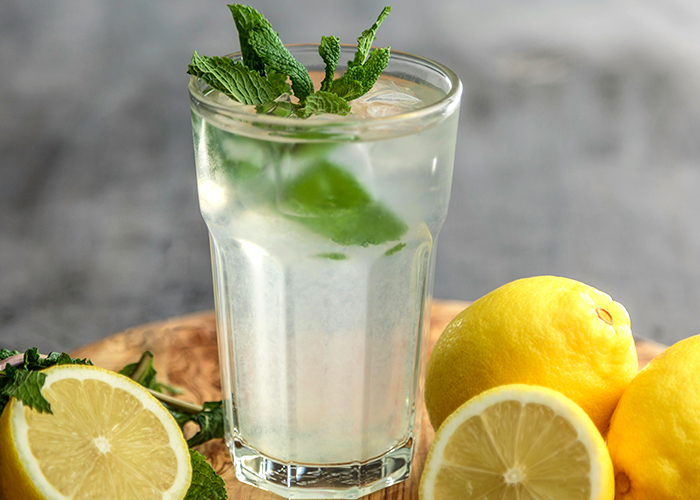 레몬물이 담긴 컵과 레몬들이 놓여있다