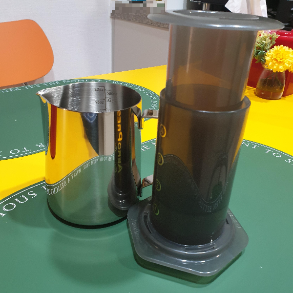 노란 테이블 위에 에어로프레스와 스팀피처