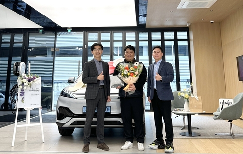 전시장 1호 고객이 14일 BYD 강서 전시장 인도 기념식에서 관계자들과 함께 기념 촬영을 하고 있다.