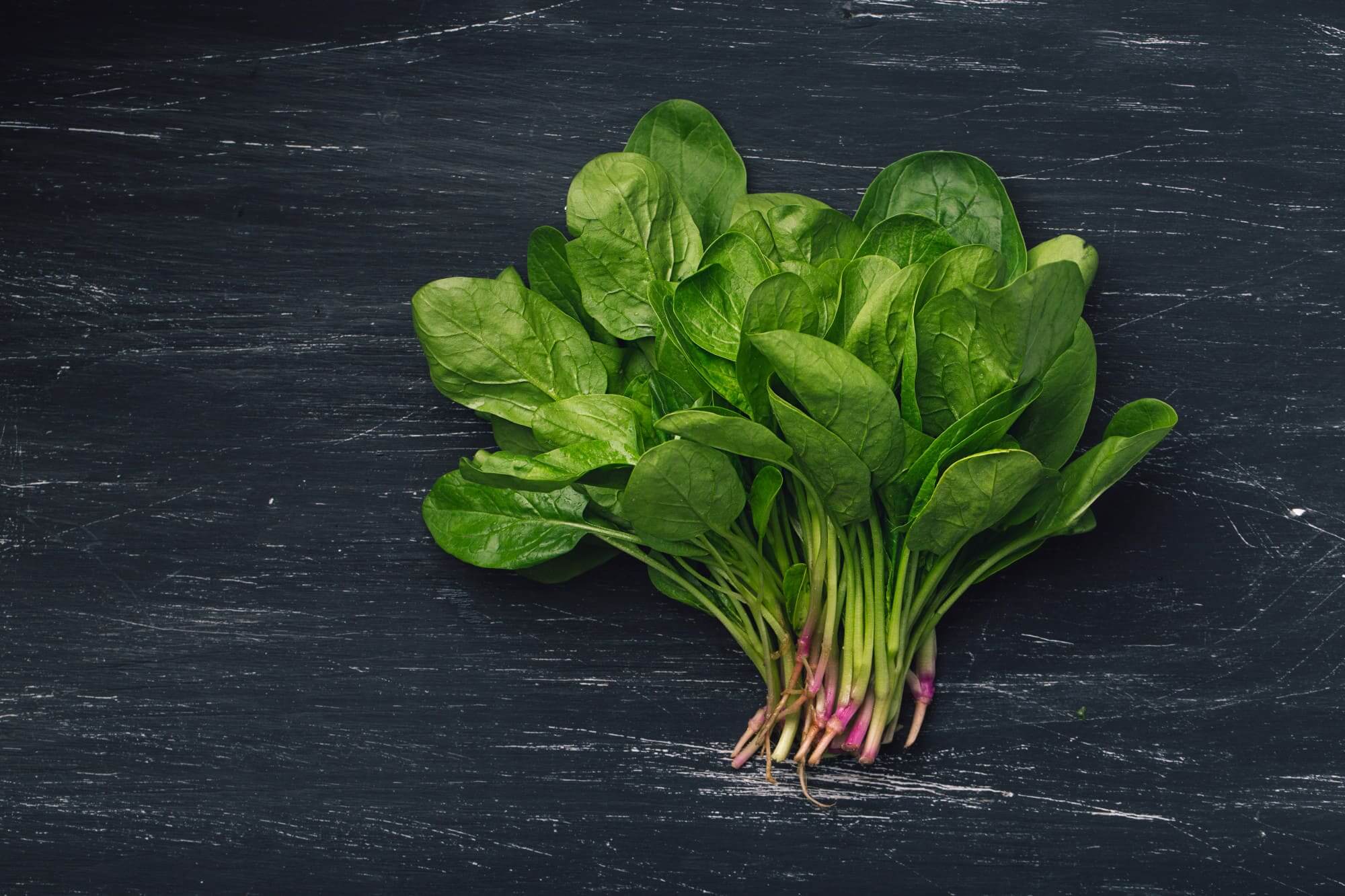 신선한 생 시금치 한줌, 검은 나무 배경 위에 놓인 모습