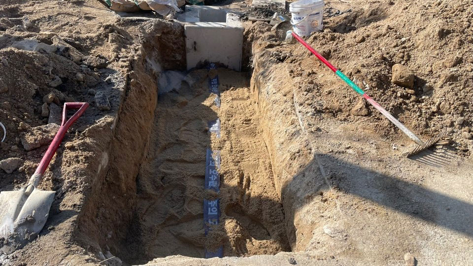 오수 배관 시공 현장에서 배관 파손과 지반 침하를 막기 위해 터파기 바닥에 고운 모래를 채워 보양 작업을 마친 모습
