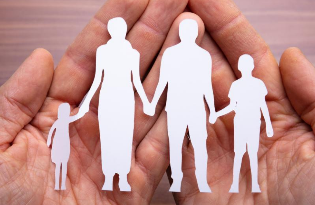 한 손에 4인 가족 종이 인형이 놓여있다.