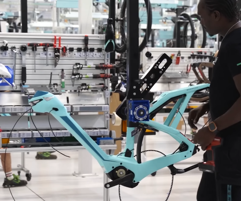 비앙키 고유의 체레스테(Celeste) 컬러가 적용된 카본 소재 산악 자전거 프레임을 전문 제작자가 조립하고 있습니다.