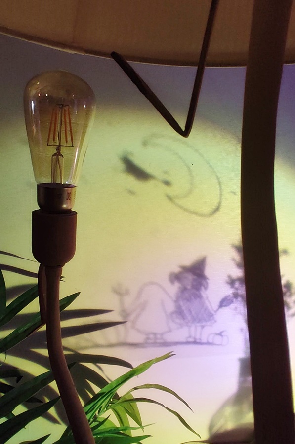 선셋 조명으로 두아이가 분장을하고 하늘을 보고 그위로 마녀가 날라다니는 그림이 벽에 비침