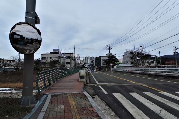 횡딘보도 앞 사능교, 앞 전신주에 반사경, 다리 건너 건물들, 전깃줄,