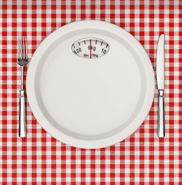 식탁 위에 저울과 포크 나이프가 놓여 있다