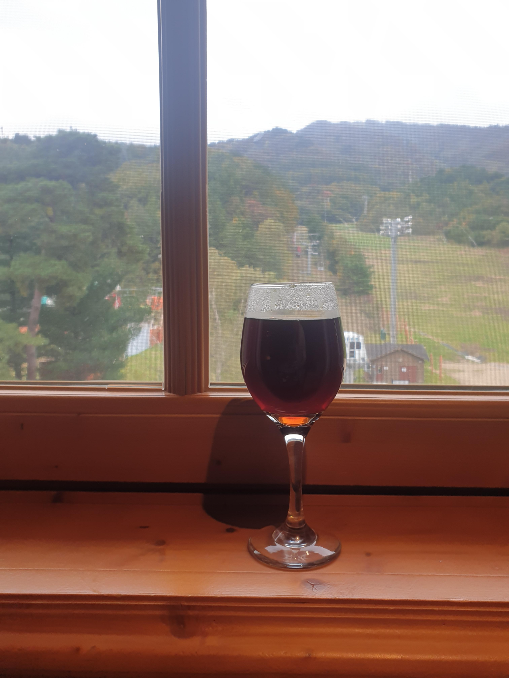 스키장이 보이는 창문 앞 와인잔에 커피가 담겨있다.