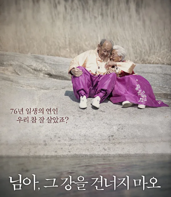 보라색 한복을 입은 조병만 할아버지와 강계열 할머니가 바위 위에 나란히 앉아 서로를 꼭 껴안고 있는 장면. 영화 《님아, 그 강을 건너지 마오》의 공식 포스터