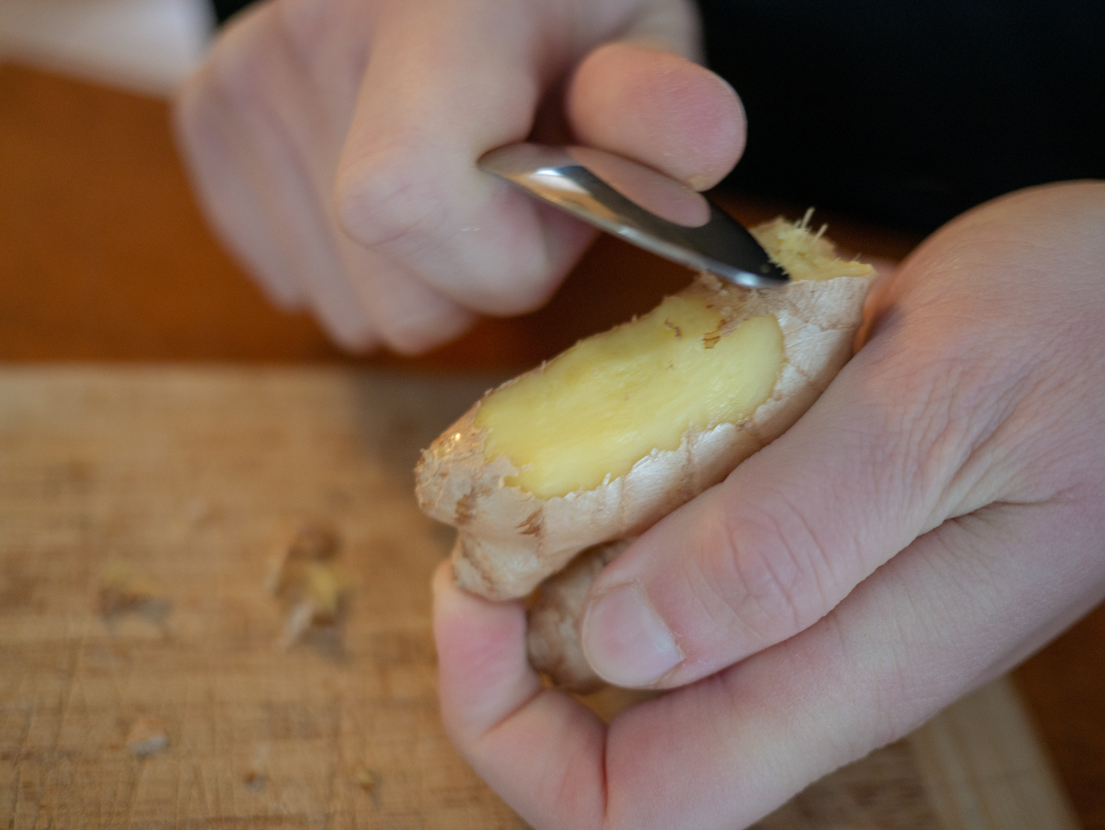 숟가락으로 생강 껍질을 벗기는 손, 노란 생강 속살이 드러난 모습