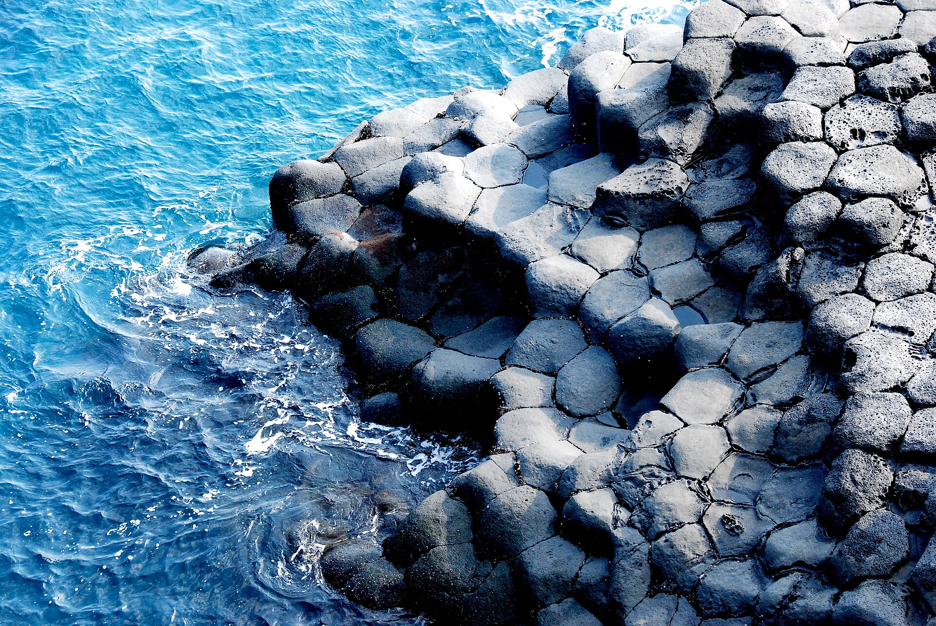Six-sided tops of basalt columns at the waterline, seen from above