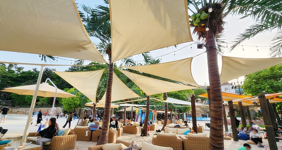 모랴사장에 야외용 소파와 테이블 멋진 천막으로 그늘을 만든 모래사장 자리