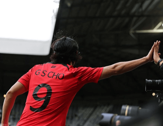 조규성 선수가 경기장에서 기뻐하며 동료 선수에게 하이파이브 하는 장면