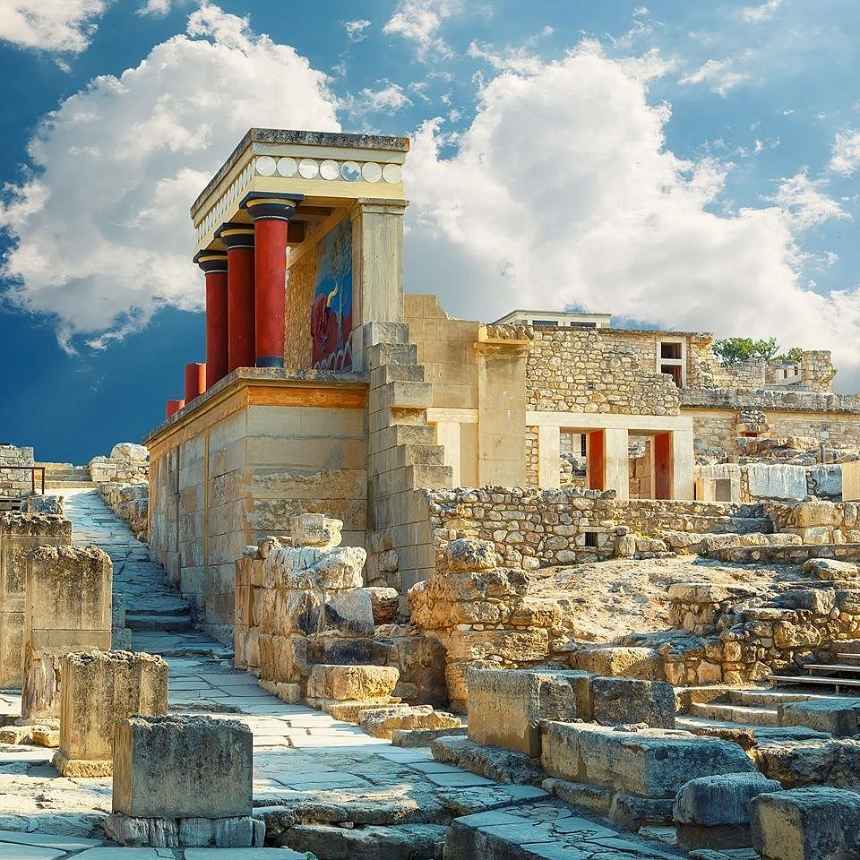 햇살 아래 복원된 크노소스 궁전 북문. 석조 유적 위로 붉은 미노아 기둥과 벽화가 있는 구조물이 푸른 하늘과 어우러져 장관을 이루고 있다.