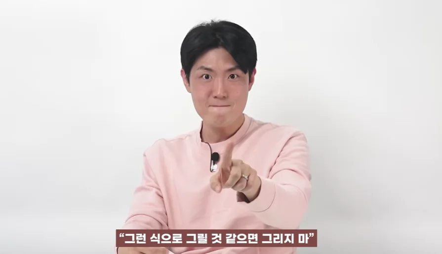 분홍색 상의를 입은 남성이 손가락으로 정면을 가리키며 '그런 식으로 그릴 것 같으면 그리지 마'라는 말을 설명하는 영상 장면