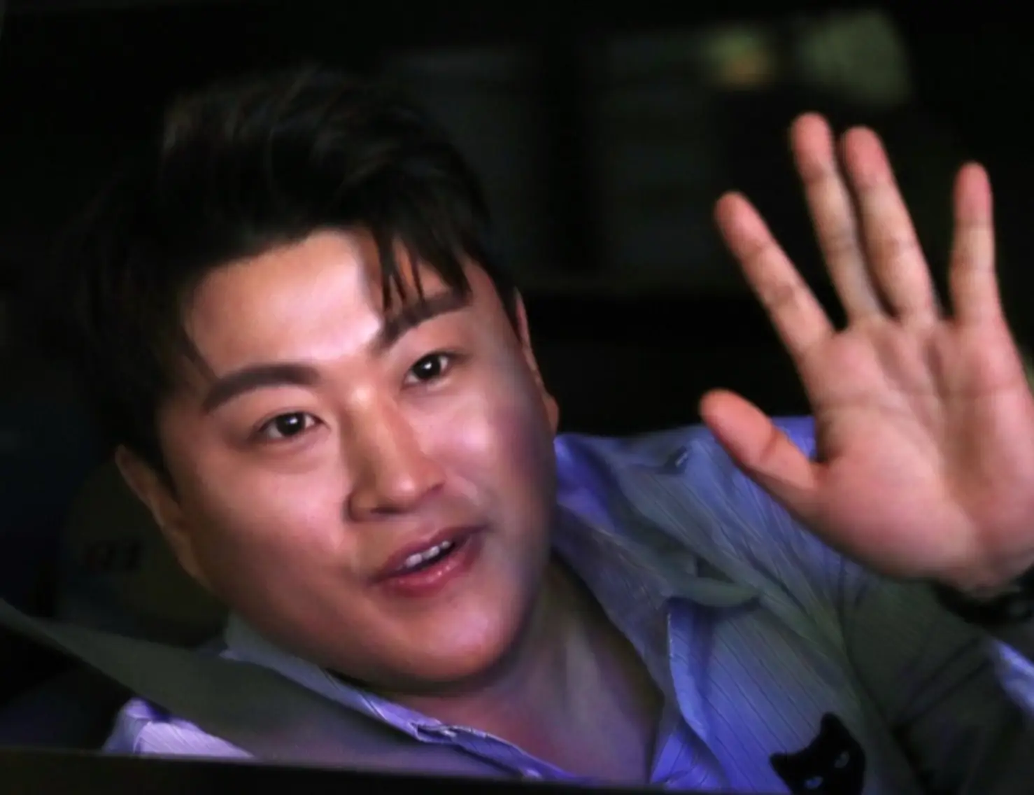 차안 안전밸트를 매고 파란 셔츠를 입은채 오른 손을 흔드는 김호중