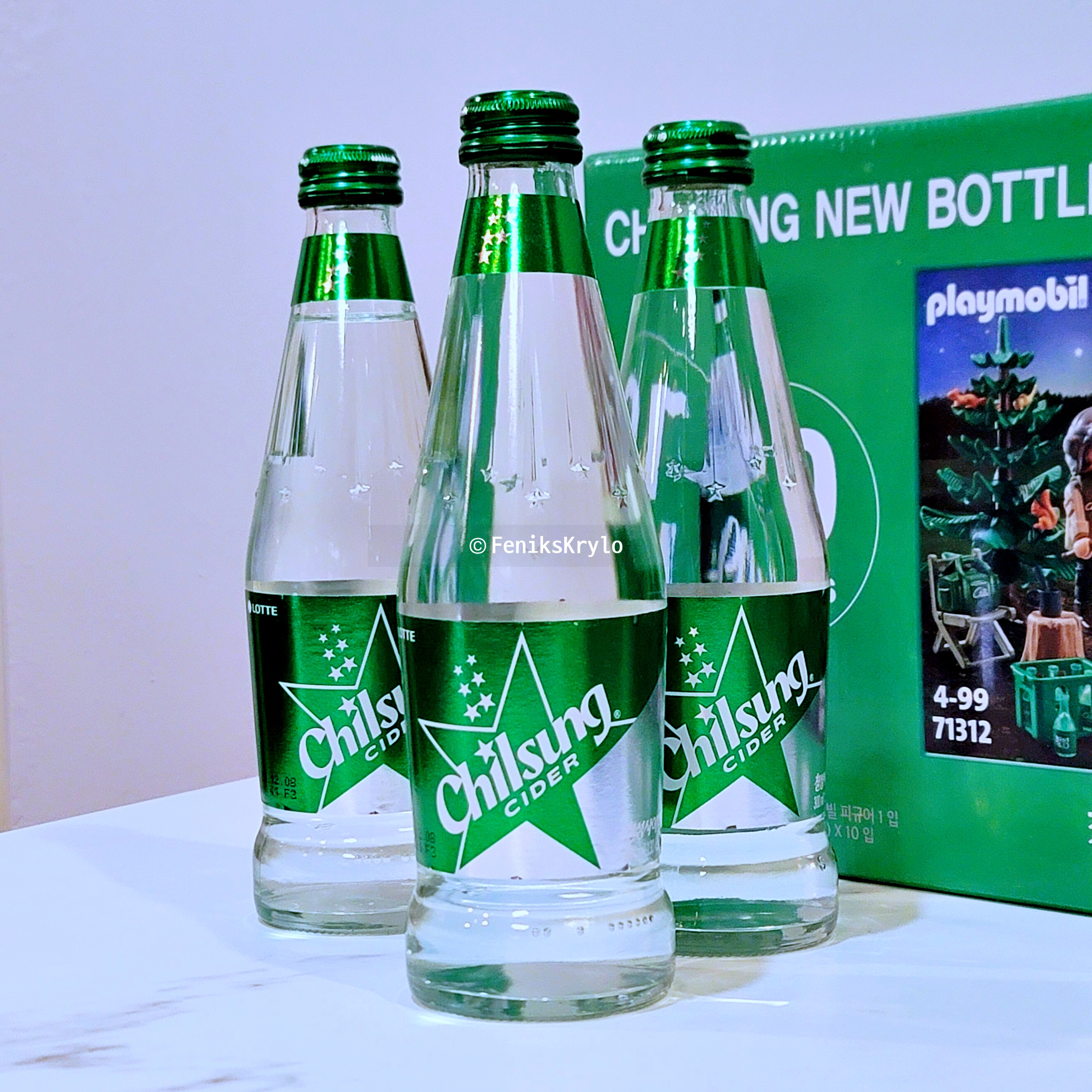롯데 칠성사이다 X 플레이모빌 - 유리병 사이다 3개가 상자 앞에 놓여있다.