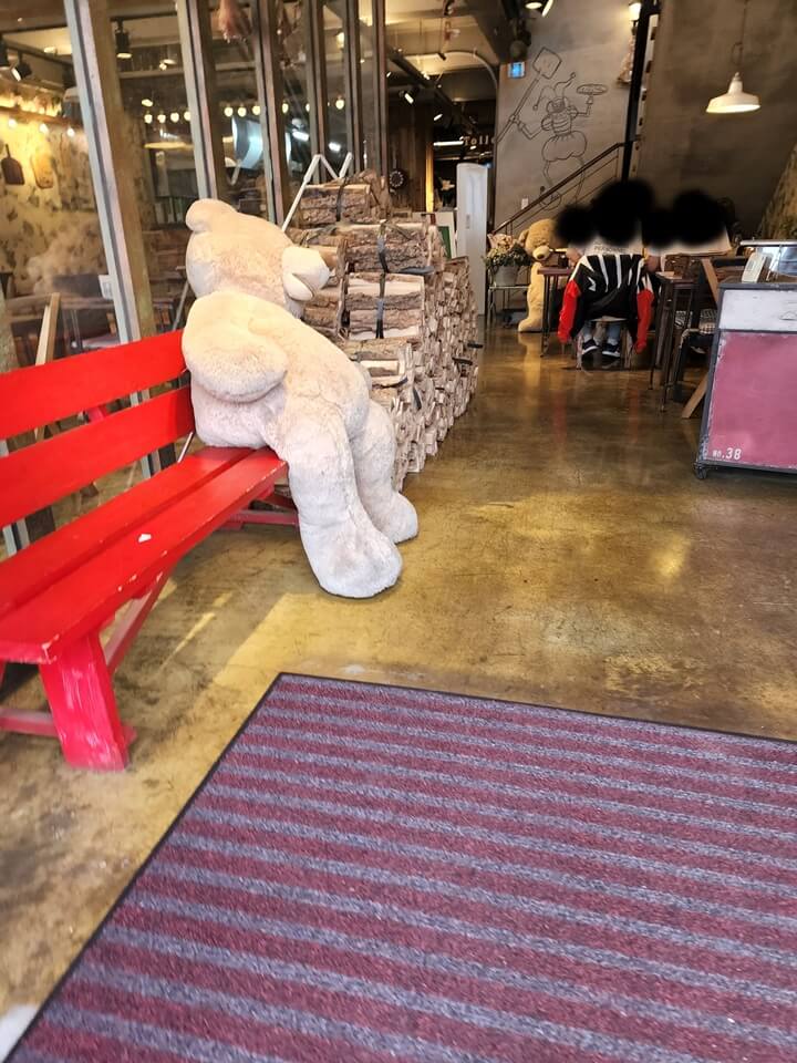 빨간색 벤치에 앉아있는 큰 곰인형