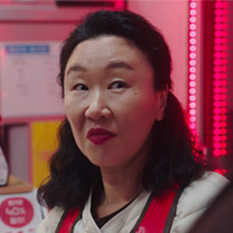 정육점을 배경으로 긴 파마머리에 누군가를 보고 있는 고기숙