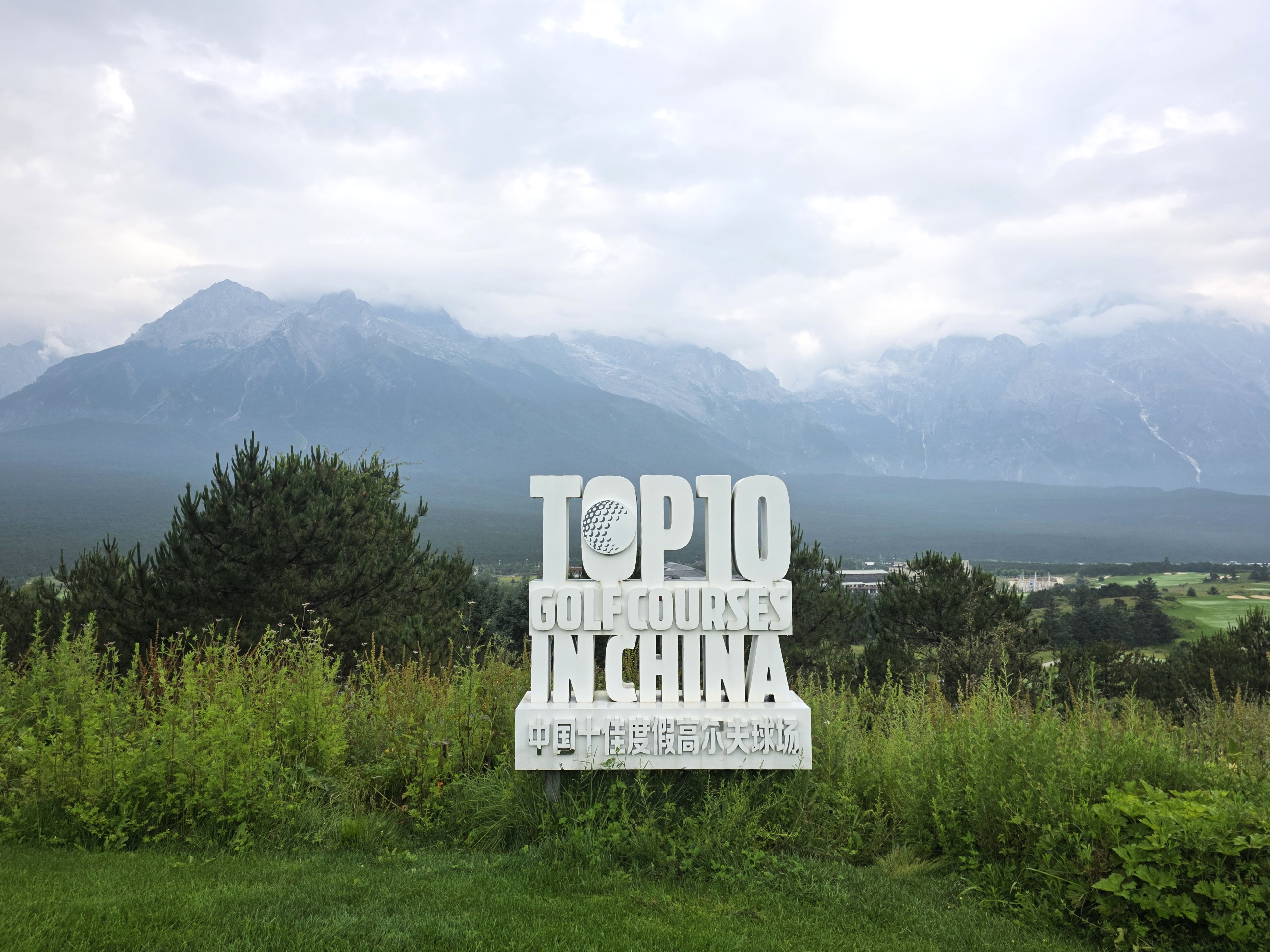 중국 운남성 여강 옥룡설산 골프장 전경. TOP10 Golf Courses in China 안내 표지판과 함께 옥룡설산이 웅장하게 펼쳐진 모습.