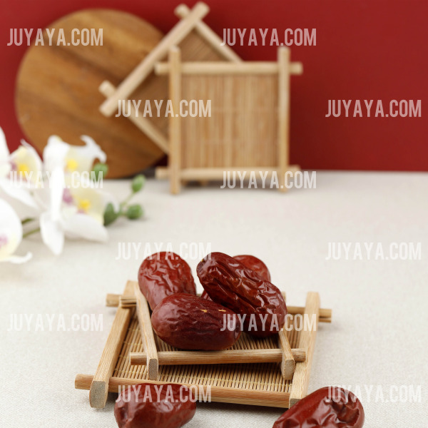 대추가 작은 대나무 쟁반 위에 놓여 있고&amp;#44; 배경에 전통적인 인테리어 장식이 있는 이미지.