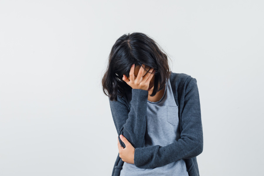 젊은 여성이 빈혈, 즉 어지럼증으로 인해서 오른쪽 손을 머리에 대고 어지럼증이 줄어들기를 기다리고 있는 것을 찍은 사진