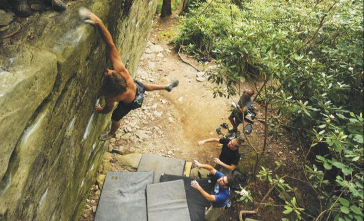 한 클라이머가 자연바위에서 런지를 하고 있는 사진