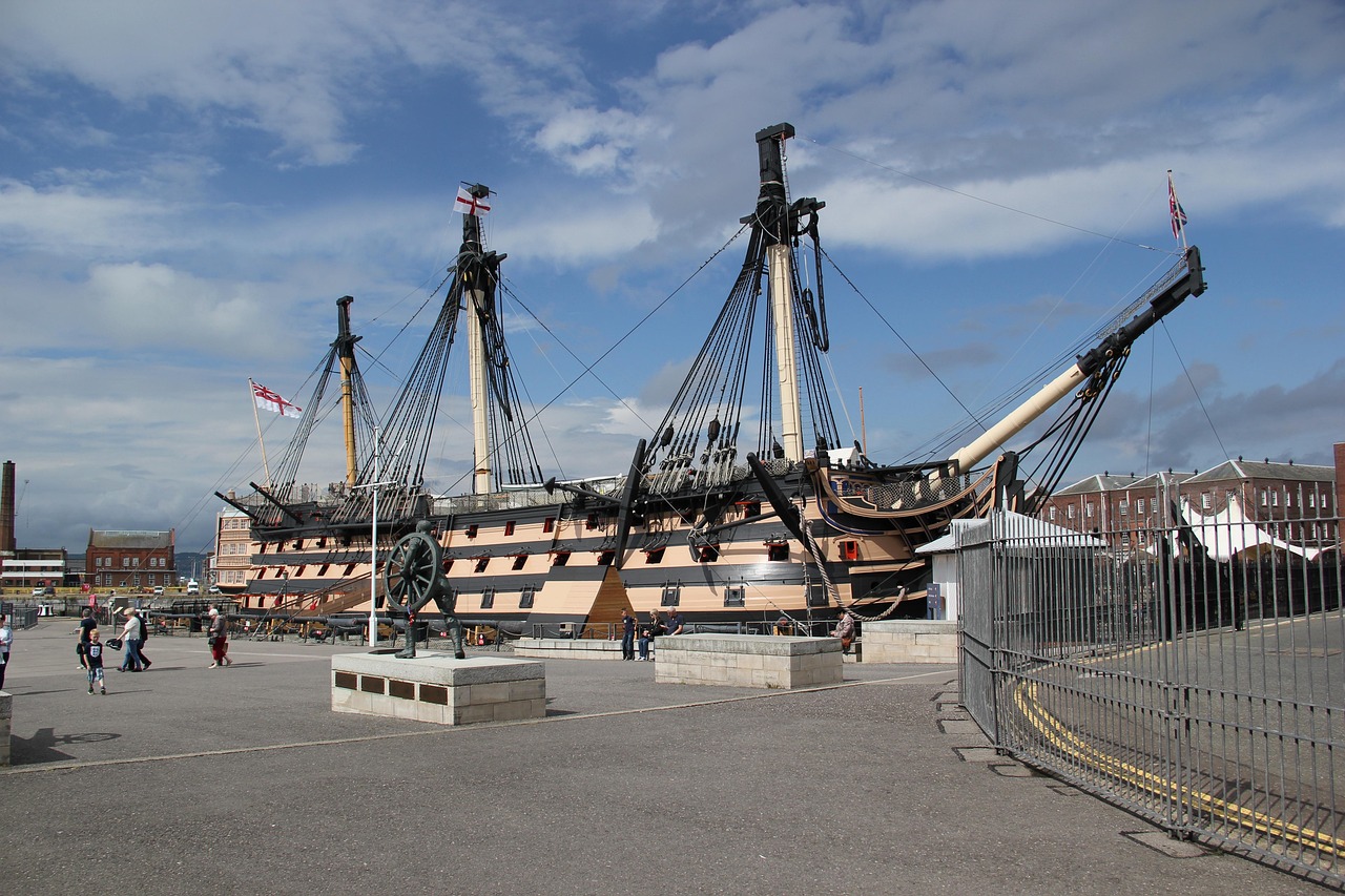 HMS Victory 전함이 포츠머스 역사 항구에 정박해 있는 모습, 방문객들이 주변을 걷고 있는 전경