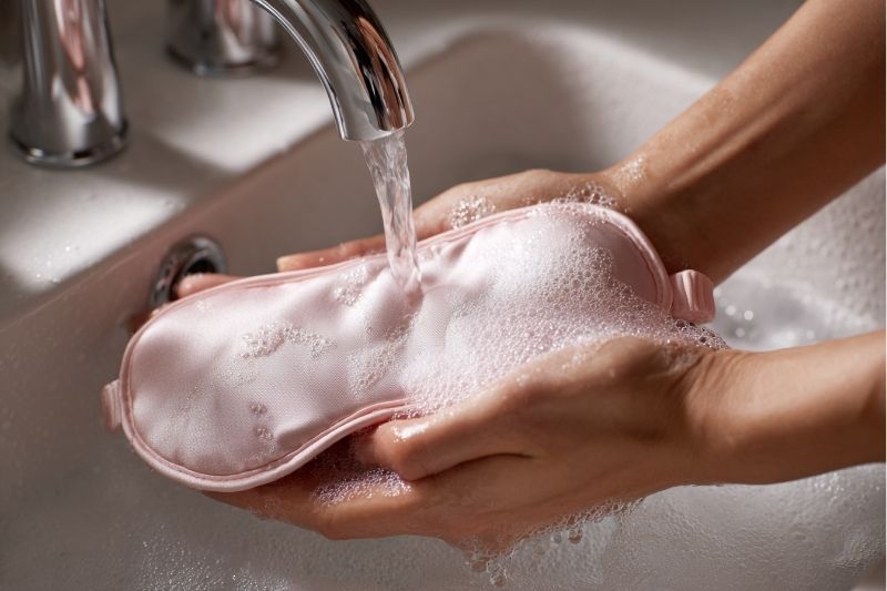 세면대에서 실크 수면 안대를 손세탁 중인 장면