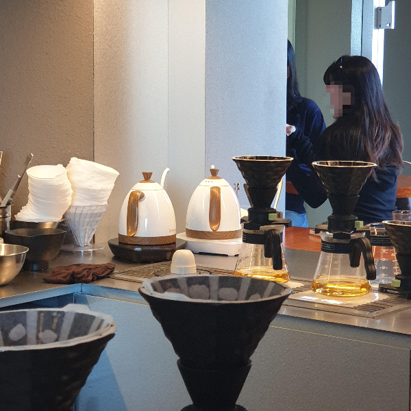 흰색 브뤼스타 드립포트 2개와 그 우측으로 두개의 드리퍼가 보인다. 앞쪽으로도 드리퍼 두개의 부분이 보인다.