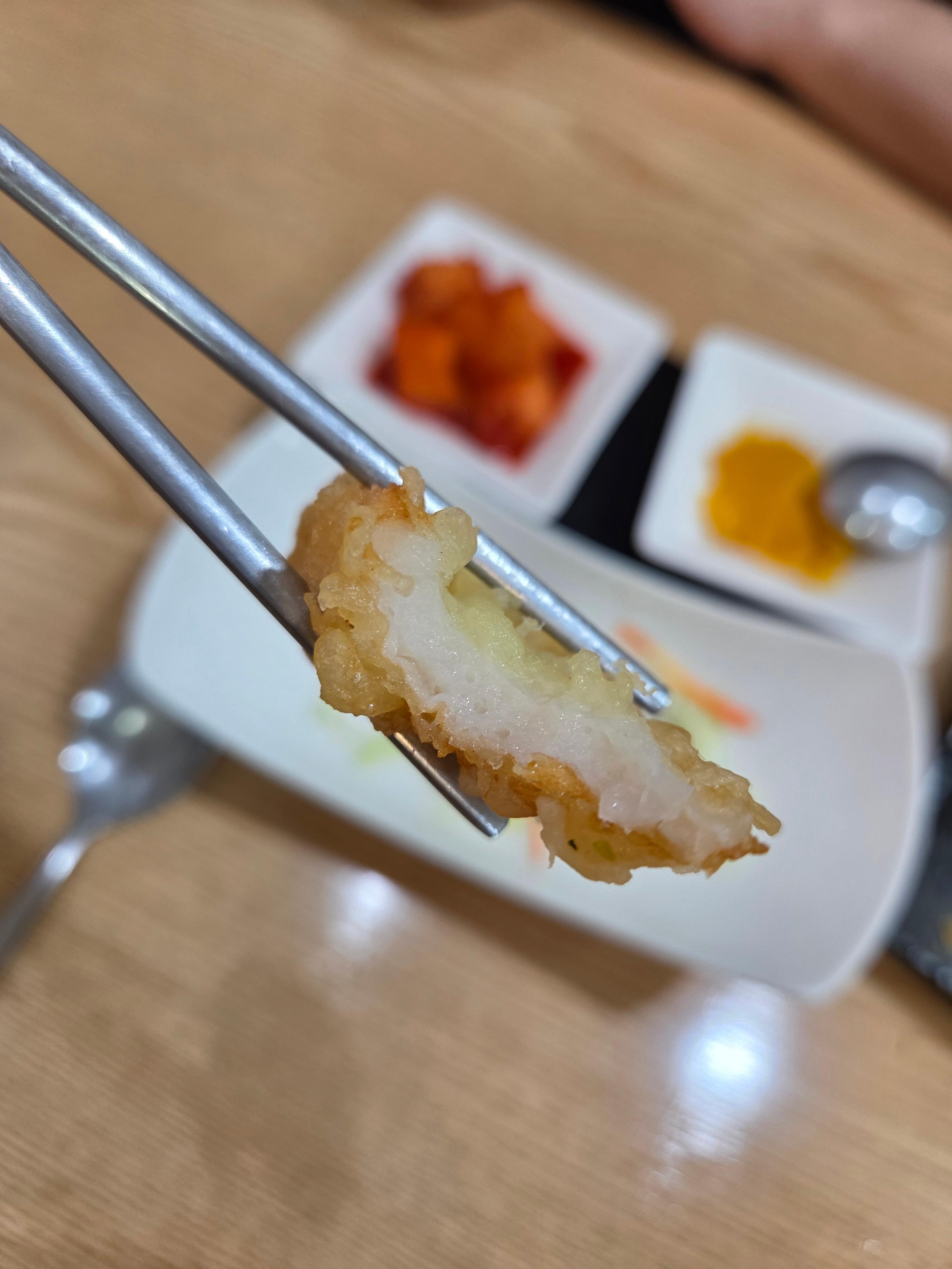 젓가락에 집은 오뎅튀김 단면과 바삭한 튀김옷 클로즈업