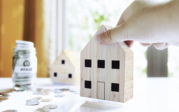 "주택 모형을 손에 들고 있는 모습과 집 마련을 위한 저금통, 주택 선택과 자금 계획을 상징하는 이미지"