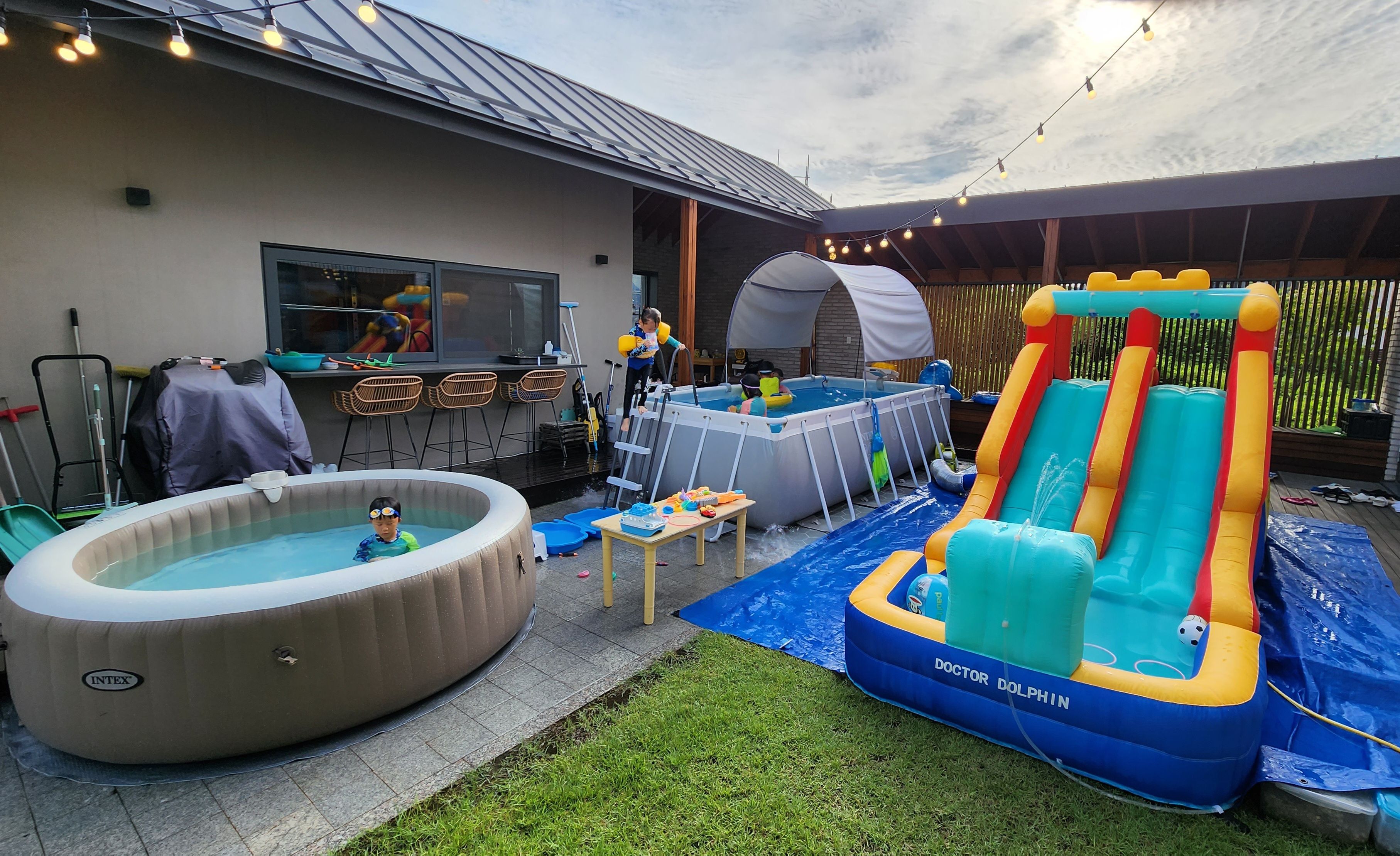 마당에 조립식 수영장을 설치해서 아이들이 수영을 즐기고 있는 모습이 담긴 사진