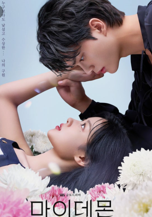 꽃 위에 누워 있는 여자 주인공과 그녀를 바로 보는 남자 주인공이 서로를 응시하고 있다.