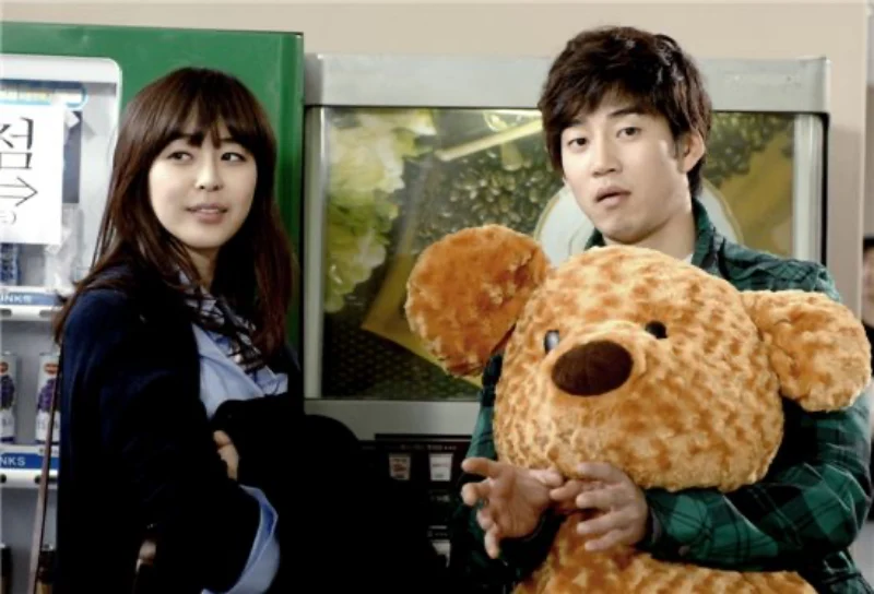 자판기를 배경으로 곰인형을 들고 있는 드라마 트리플의 윤계상
