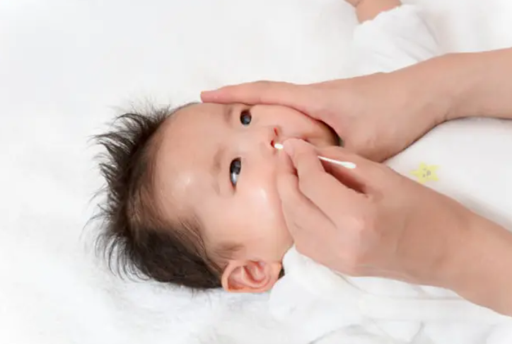 면봉으로 콧물을 제거하는 신생아