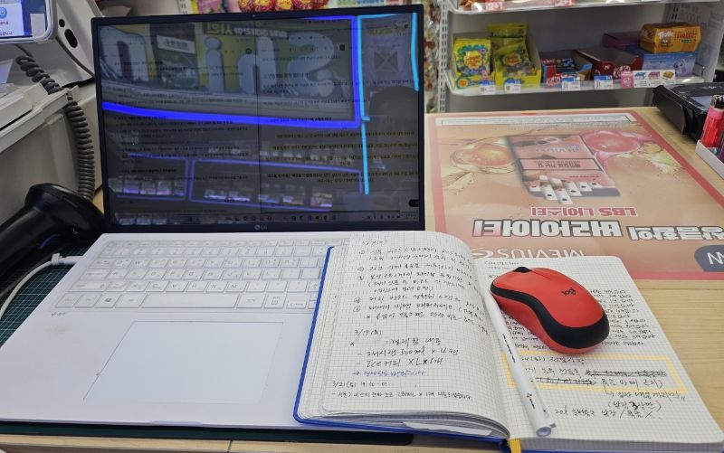 편의점 포스기 앞 노트북과 나란히 놓인 사장님의 업무 노트의 모습. 명절 연휴 기간 중 남은 재고 리스트와 부족했던 품목, 알바생 운영 피드백 등을 꼼꼼하게 기록하여 내년 매출 극대화를 위한 '시즌 대응 매뉴얼'을 완성해가는 과정 예시.