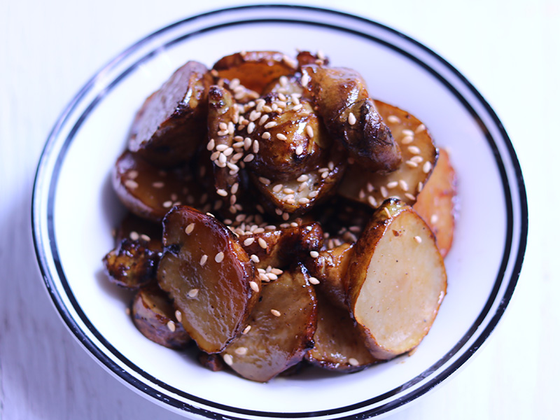 돼지감자 오븐 볶음. 흰접시에 깨를 뿌려 담았다.