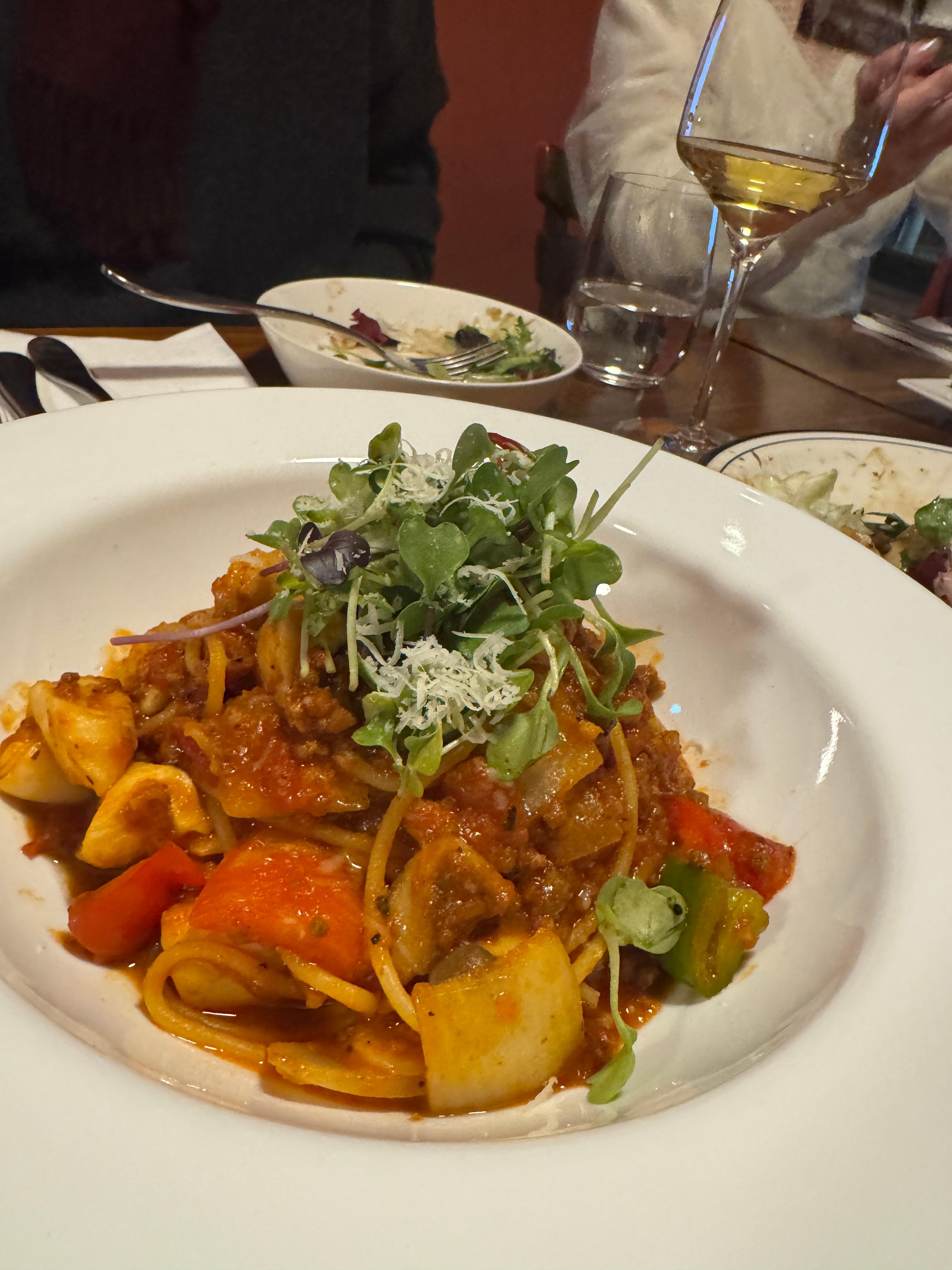 토마토 베이스 파스타 한 접시&amp;#44; 링 모양 해산물과 파프리카&middot;채소 토핑&amp;#44; 위에 마이크로채소와 치즈가 올라간 모습