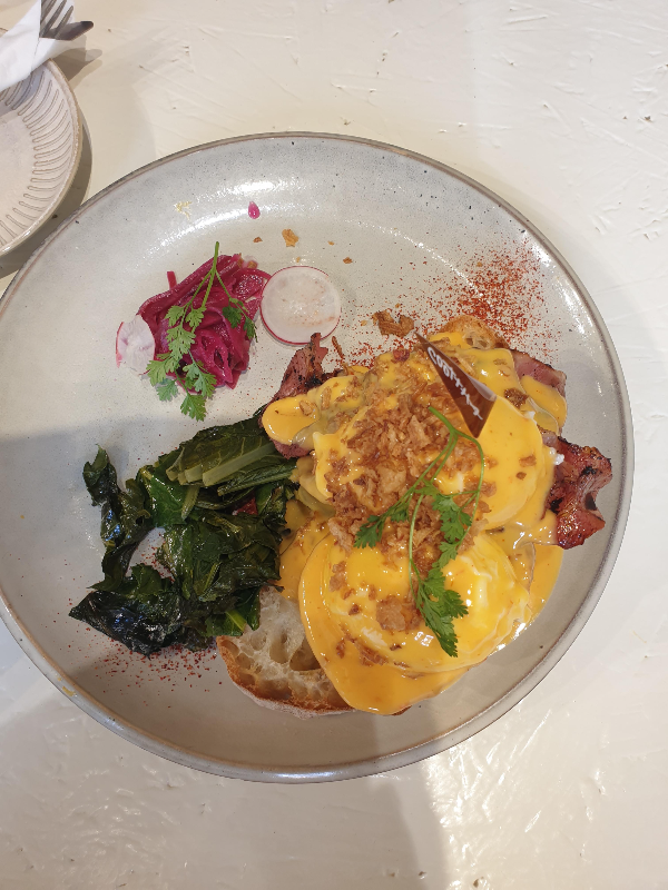 접시위에 수란이 올라간 쿳사 베네딕트가 올려져 있다. 붉은 시즈닝이 맛을 돋군다.