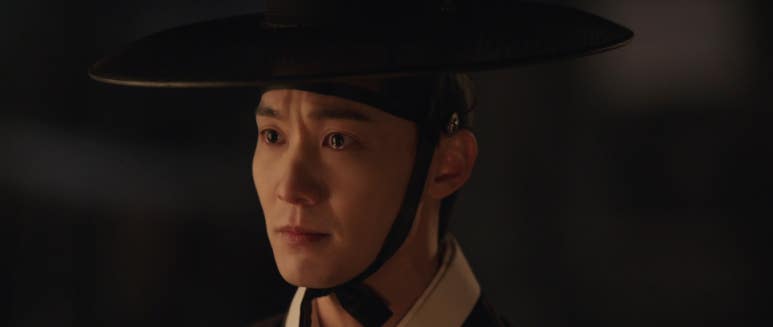 갓을 쓴 남성이 감정을 억누르는 듯한 애틋한 표정을 짓는 모습