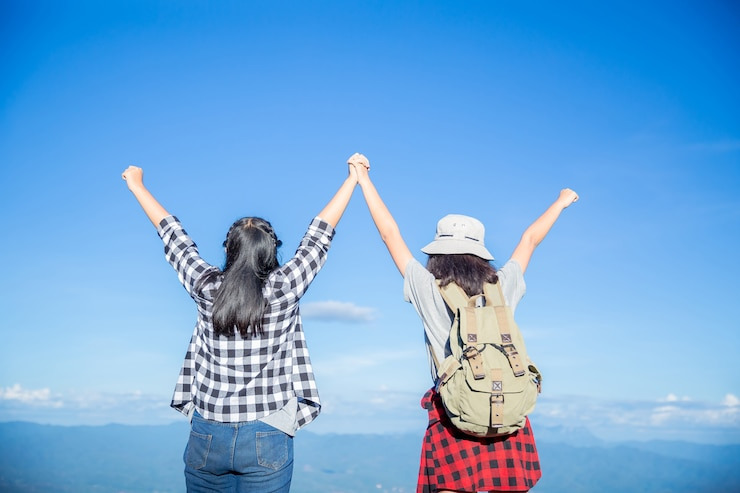 두 명의 여성이 바다를 보며 손을 올린 이미지