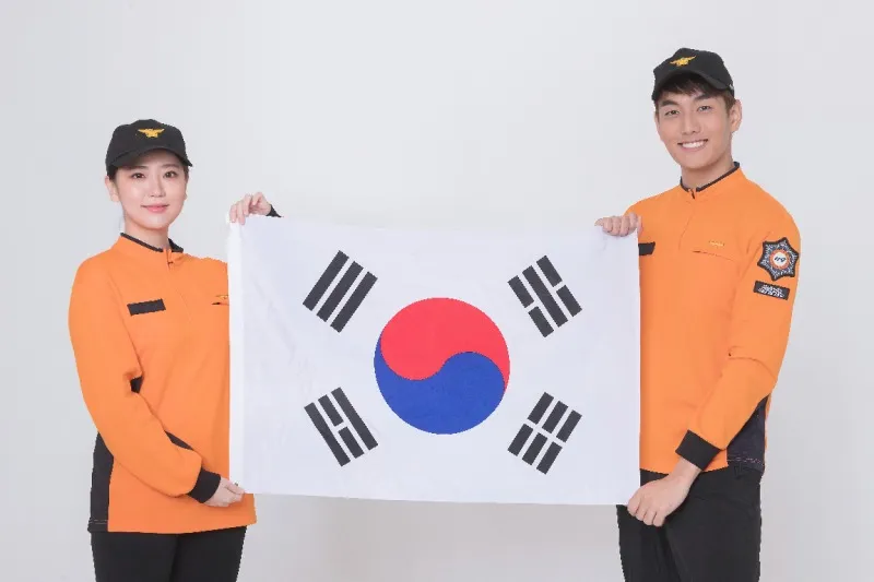 태극기 앞에서 수어 신고를 안내하는 소방대원 두 사람