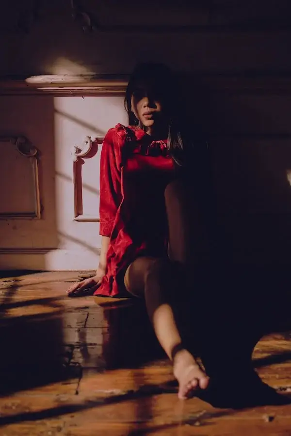 여자가 불꺼진 방 가구에 기대어 우울해 하고 있다