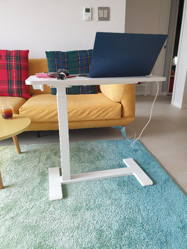 노란 쇼파 앞에 사이드 테이블이 놓여있다. 테이블 위에는 노트북 마우스 그리고 스마트폰이 올려져 있다.