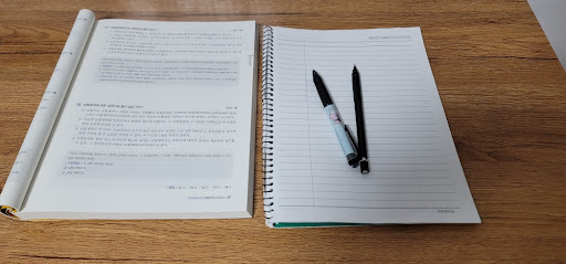 책상 위에 펼쳐진 교재와 노트, 펜