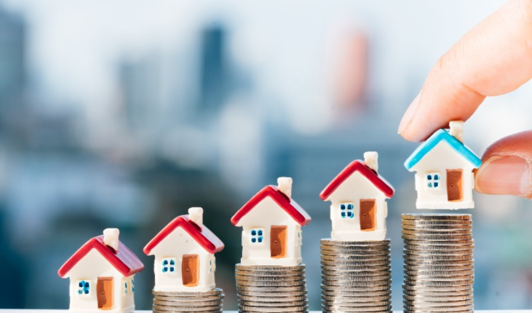 동전을 쌓아올리고 그 위에 집 모양 소품이 놓여있다.