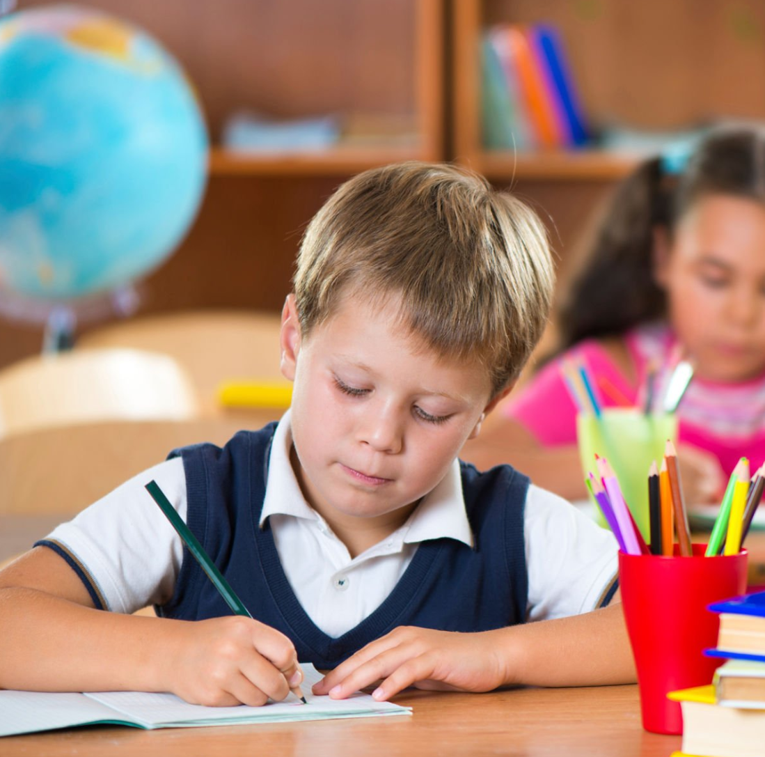 책상에 앉아서 공부하는 초등학생 사진