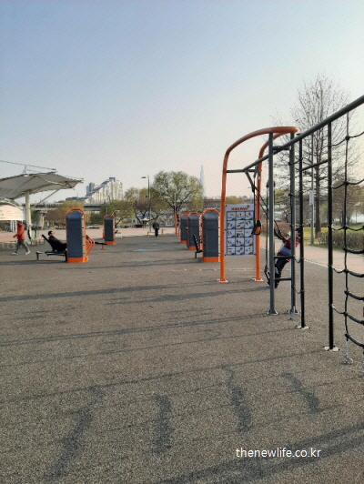 People exercising with outdoor fitness equipment at Hangang Kwangnaru Health Park-한강 광나루 야외 헬스장에서 사람들이 하체 근력 운동 기구를 사용하는 모습